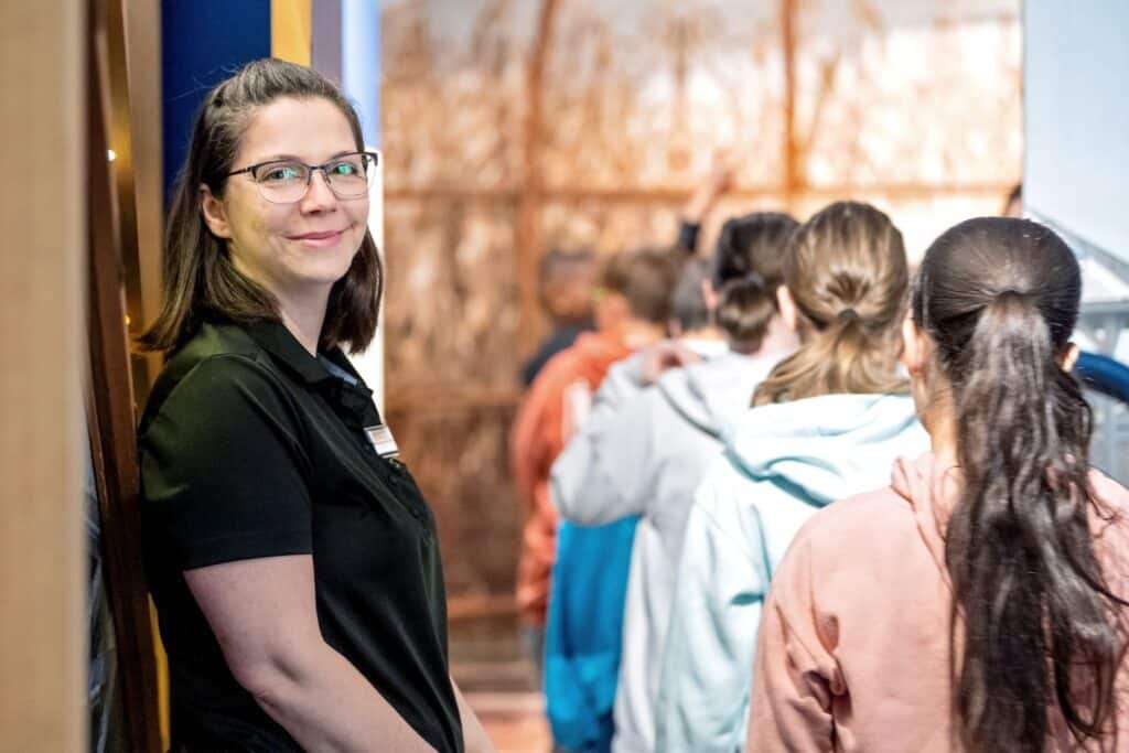 L'animatrice ouvre la porte de l'exposition pour laisser entrer les élèves